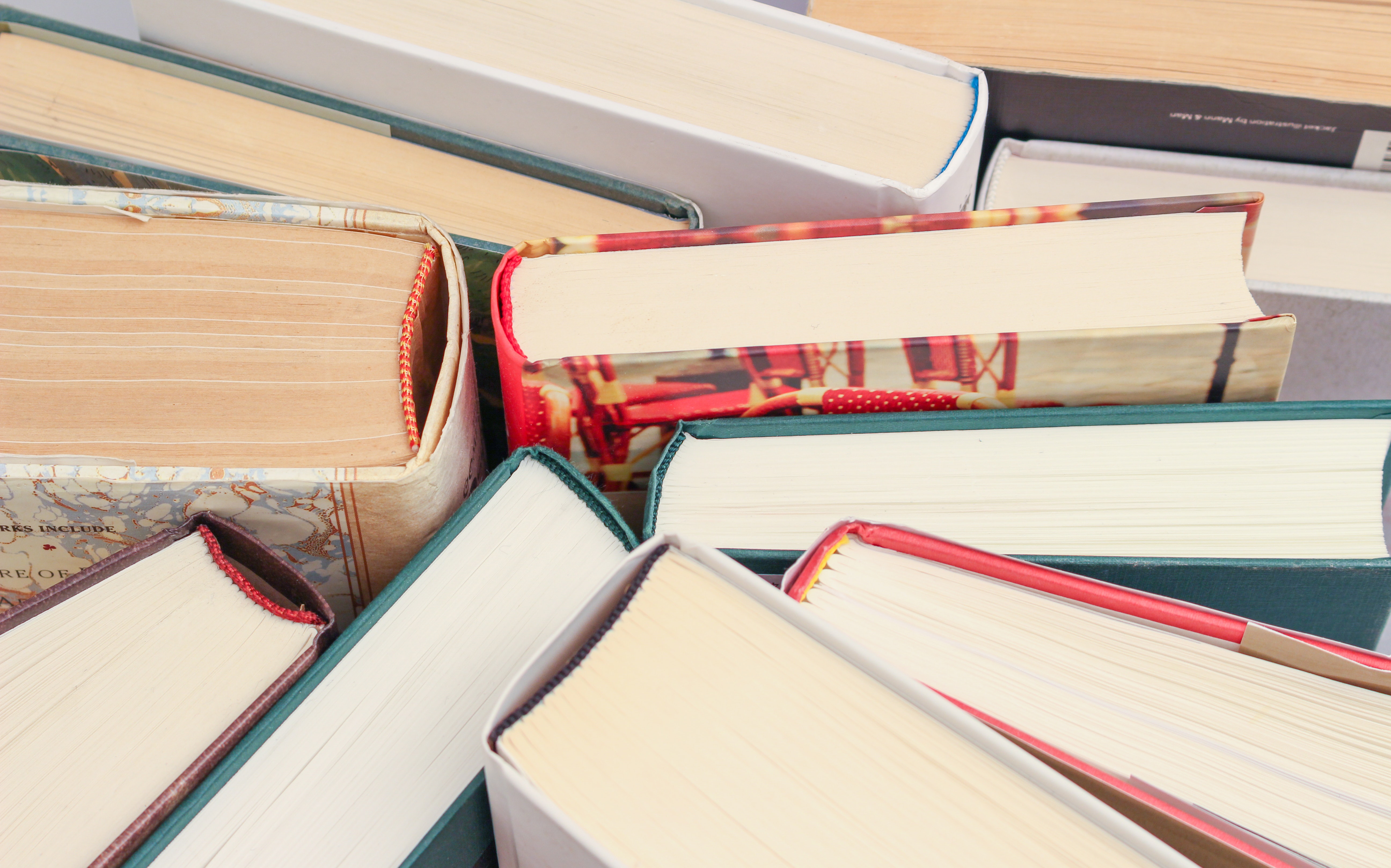 An overhead photograph of a stack of paperbacks with red and cream bookmarks.